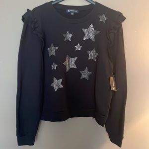 Black sweatshirt material with a ruffled shoulder and glitter stars